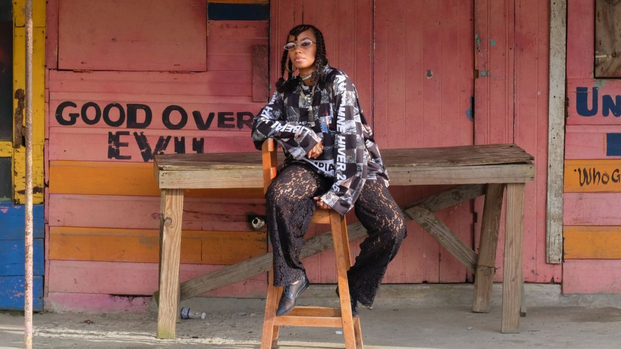 Photo of a woman sitting in front of a colorful wooden building.