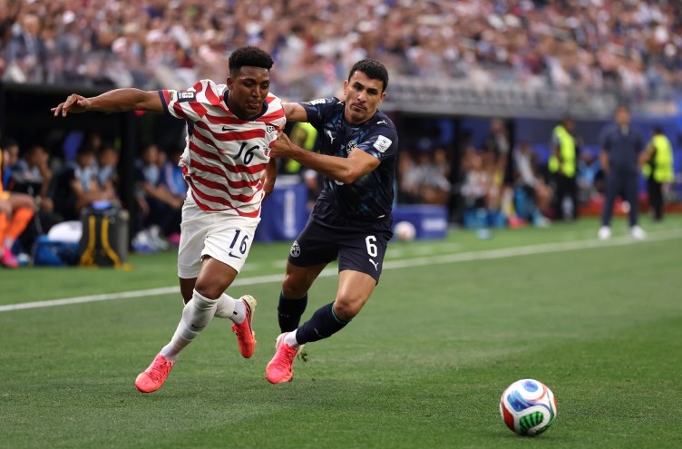 a U.S. soccer player dribbles a ball past a Paraguayan defender on a soccer field