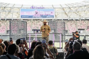 photo of singer Carín León speaking onstage in front of a crowd holding up cell phones inside Miami's Nu Stadium