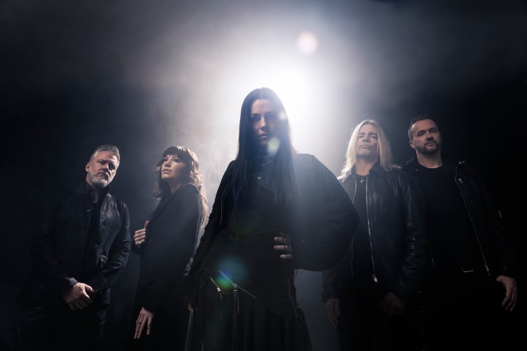 photo of band Evanescence wearing black inside a black room with one light shining behind them