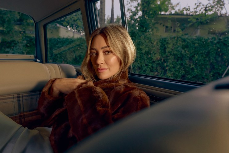 photo of singer Hilary Duff posing in a fur coat in the backseat of a car