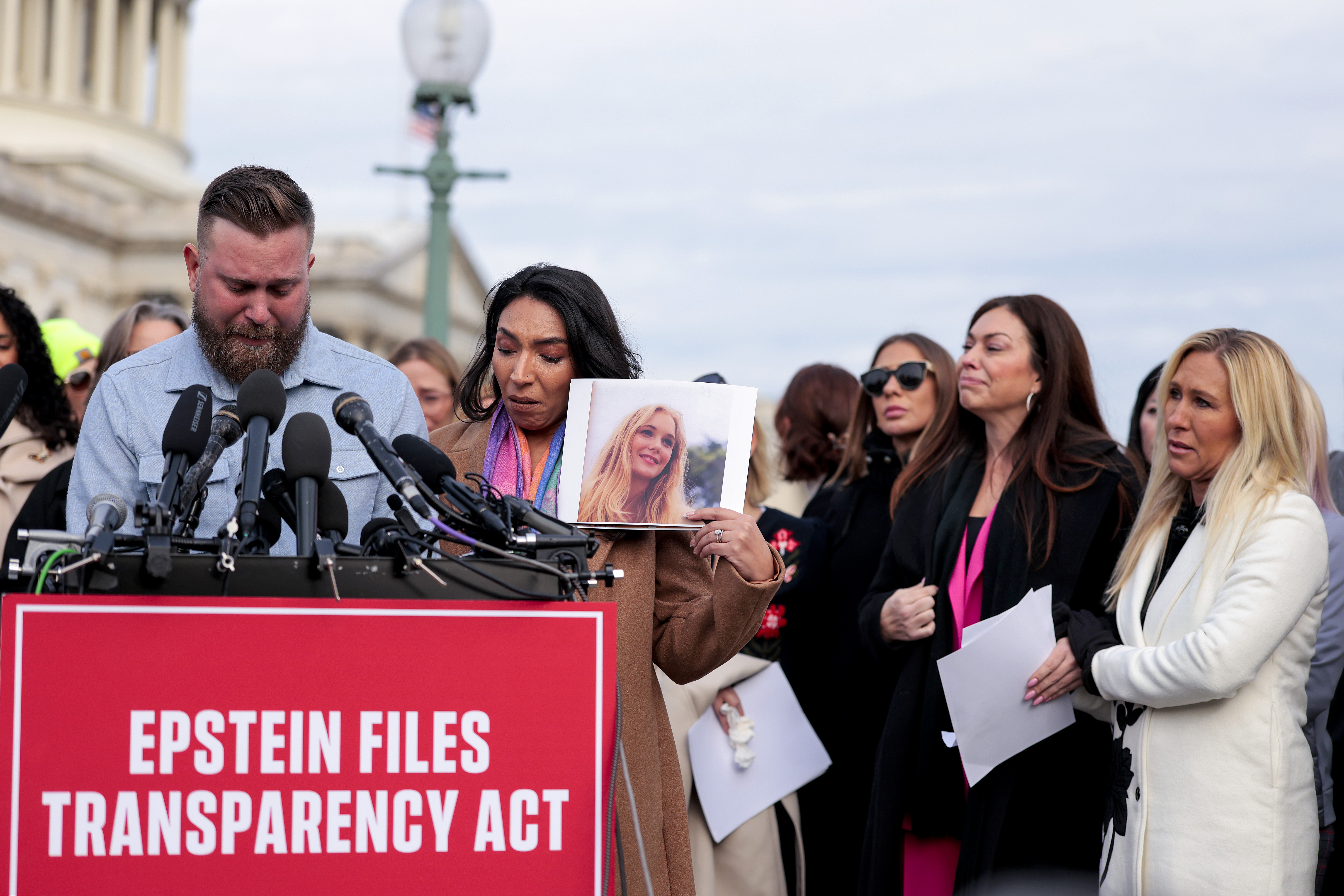 Sky Roberts (L), brother of Virginia Giuffre, who was abused by Jeffrey Epstein, and his wife Amanda Roberts hold up a photo of Giuffre as they speak during a news conference with lawmakers on the Epstein Files Transparency Act outside the U.S. Capitol on November 18, 2025 in Washington, DC.