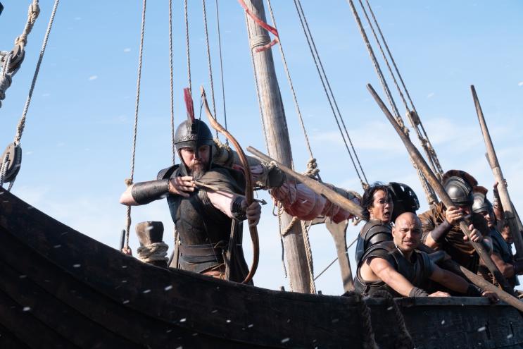 film still depicting Matt Damon as Odysseus slinging arrows from a ship under siege in Christopher Nolan's "The Odyssey"