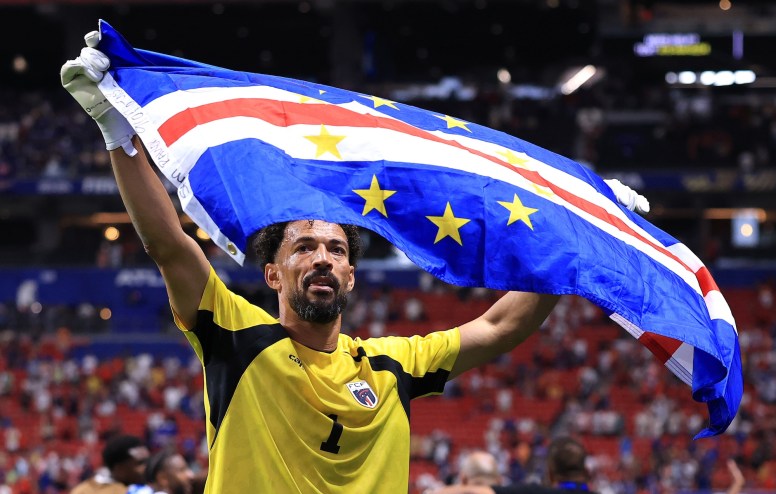 a professional soccer player holds up the Cabo Verdean national flag