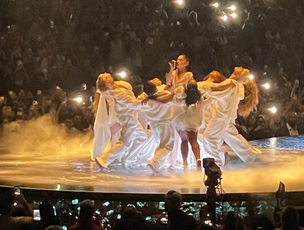 photo of singer Ariana Grande singing on stage surrounded by dancers