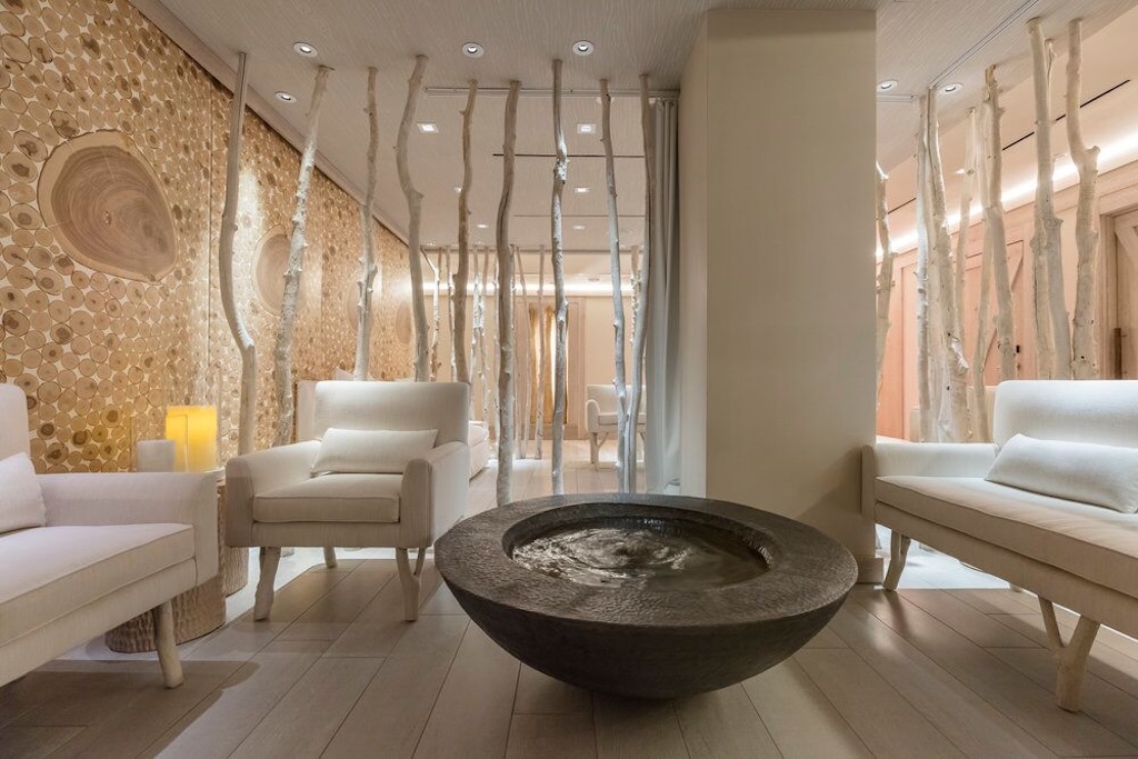 photo of a spa lobby showing a basin with water and three couches with painted tree trunks as decor behind them
