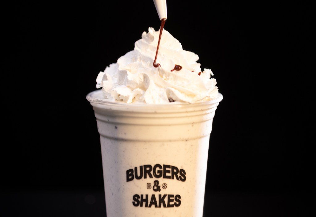 a milkshake with whipped cream on top and a chocolate drizzle