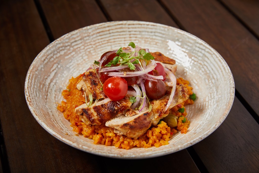 a yellow rice dish with toppings on a wood table inside of a white bowl