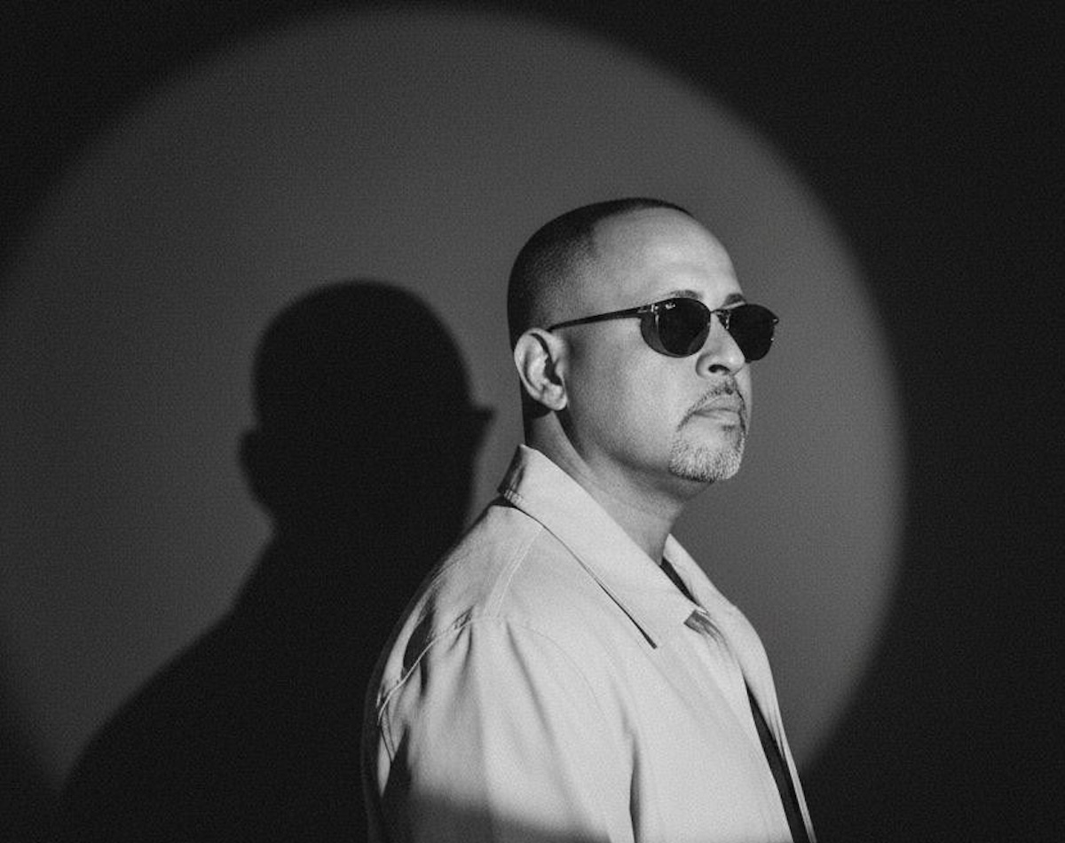 Black and white portrait of a man with very short hair and sunglasses.