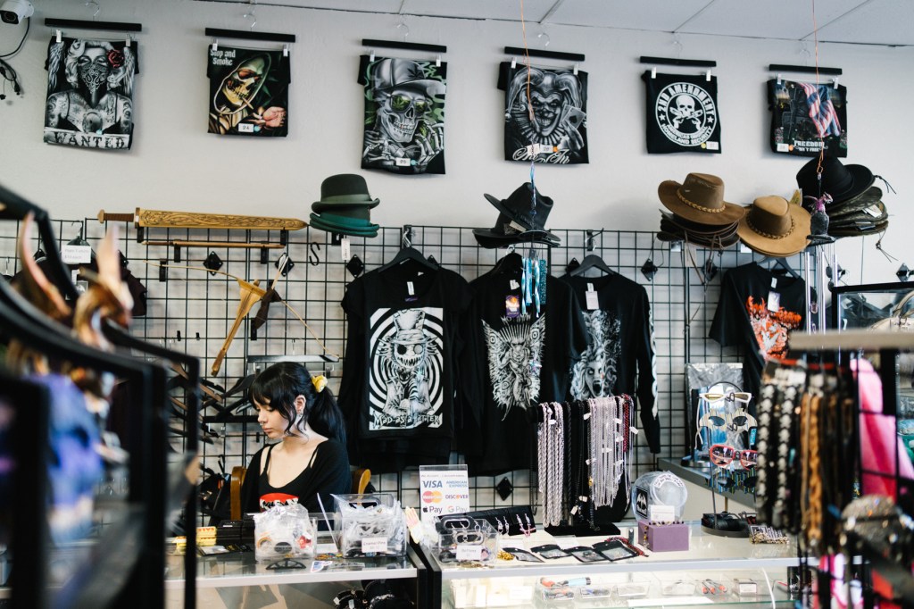 photo of a cashier behind the counter at a store selling shirts and hats geared toward the alternative scene