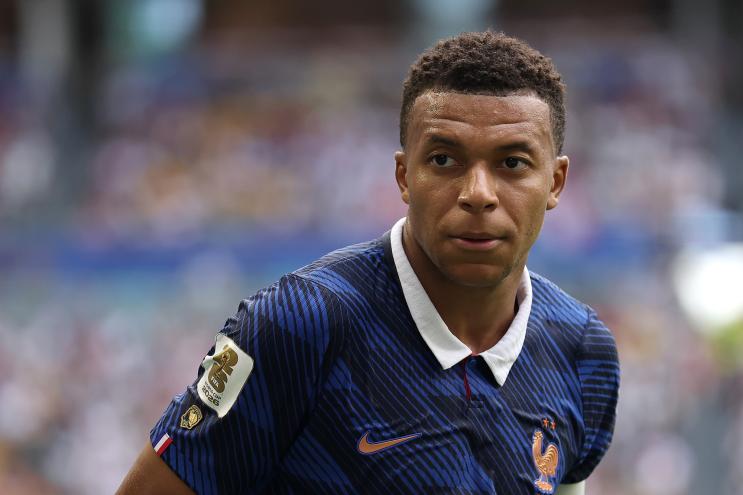 A photo of a Black man in a soccer jersey on a field.