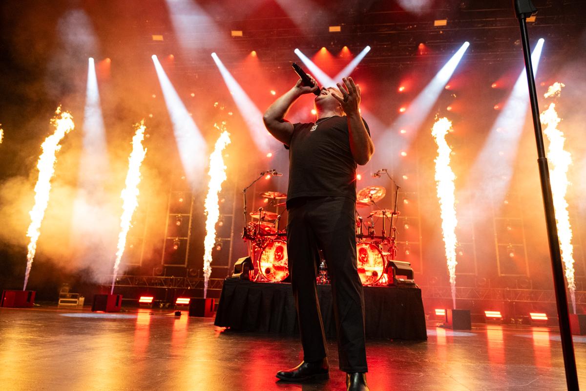 Photo of the singer of Disturbed singing on stage in front of flames.