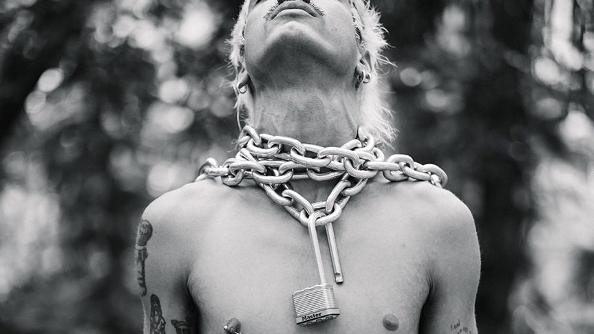 black-and-white photo of model Brian Linares posing with a thick metal chain and open lock around his neck
