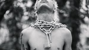 black-and-white photo of model Brian Linares posing with a thick metal chain and open lock around his neck