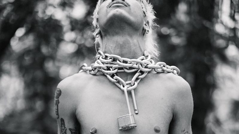 black-and-white photo of model Brian Linares posing with a thick metal chain and open lock around his neck