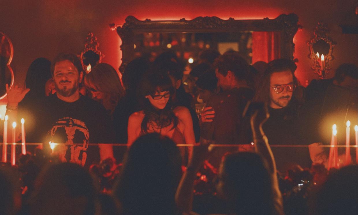 Photo of three people behind the turntables under red lights in Miami.