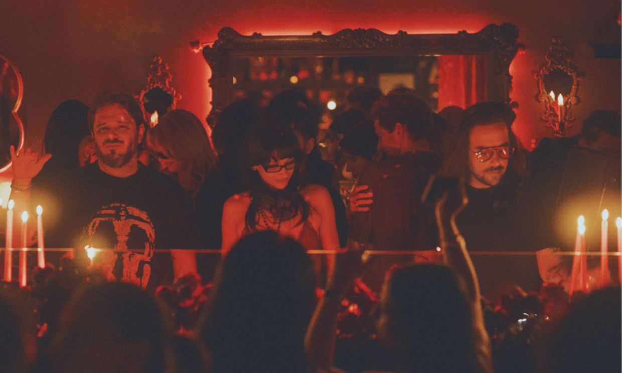 Photo of three people behind the turntables under red lights in Miami.