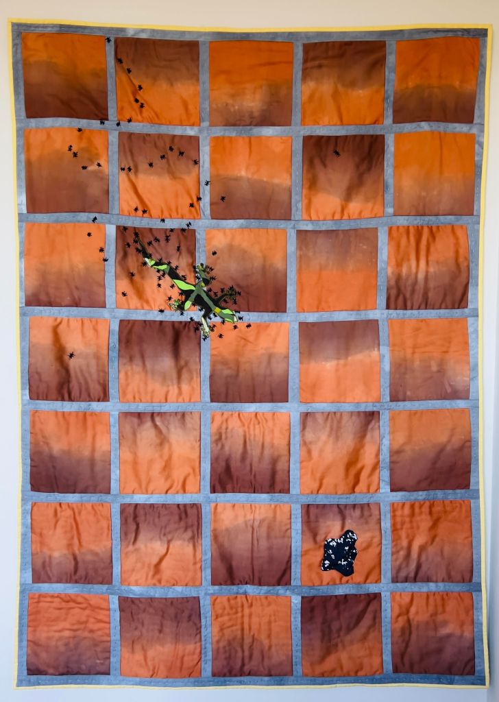 photo of a quilt depicting fabric resembling saltillo tile with a fabric lizard surrounded by ants