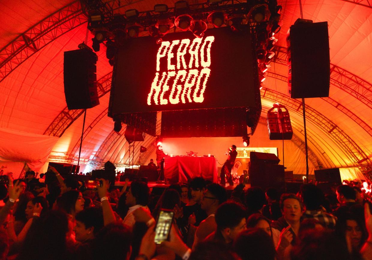 Photo of a party with red lights and an LED sign that reads Perro Negro