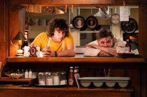 Film still from the movie "Tony depicting two men leaning on the counter of a restaurant kitchen