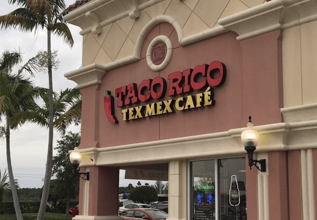 a red and beige building the words "Taco Rico" on the exterior wall
