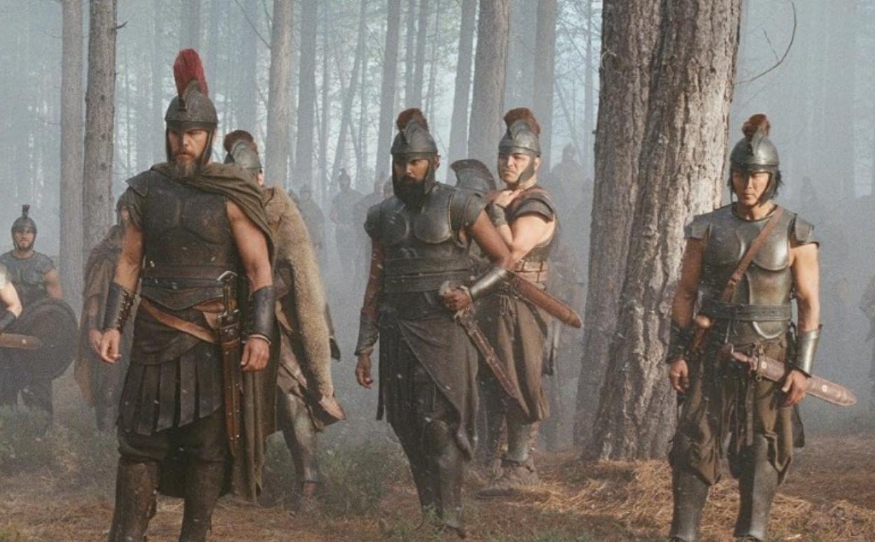 film still from "The Odyssey" depicting soldiers marching through a forest
