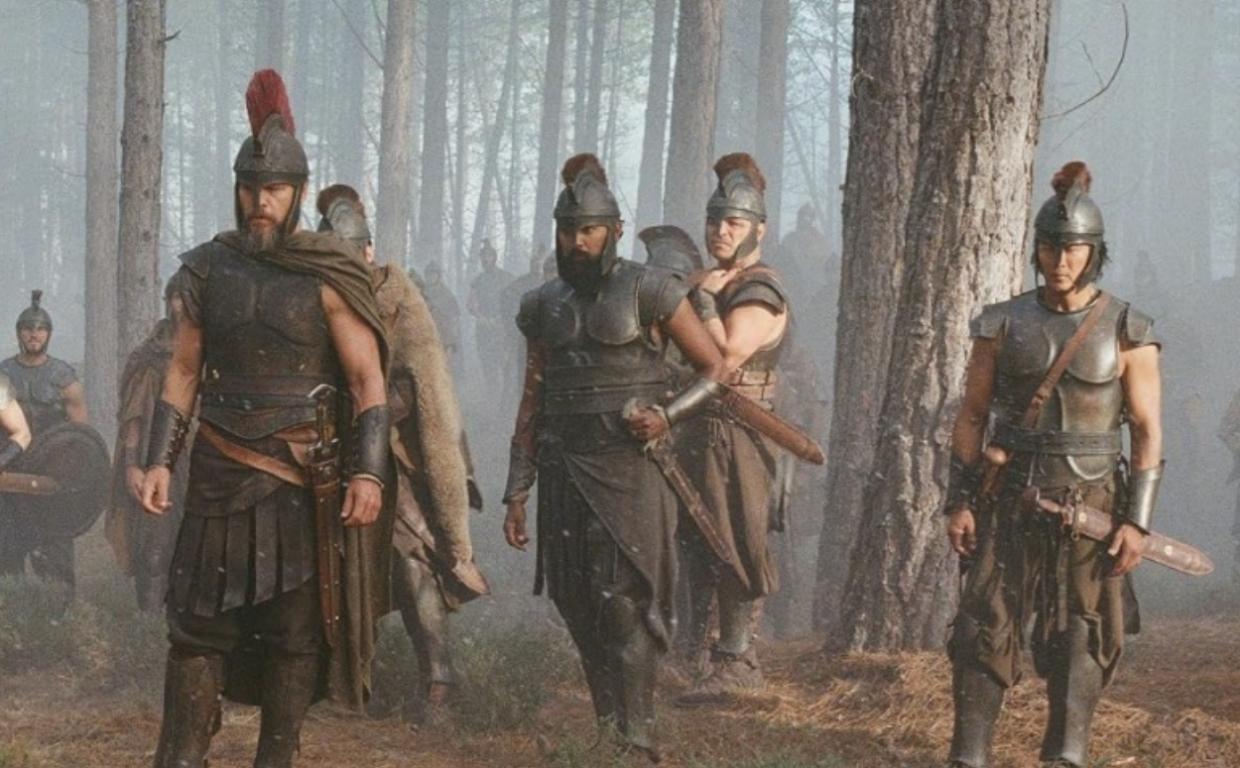 film still from "The Odyssey" depicting soldiers marching through a forest