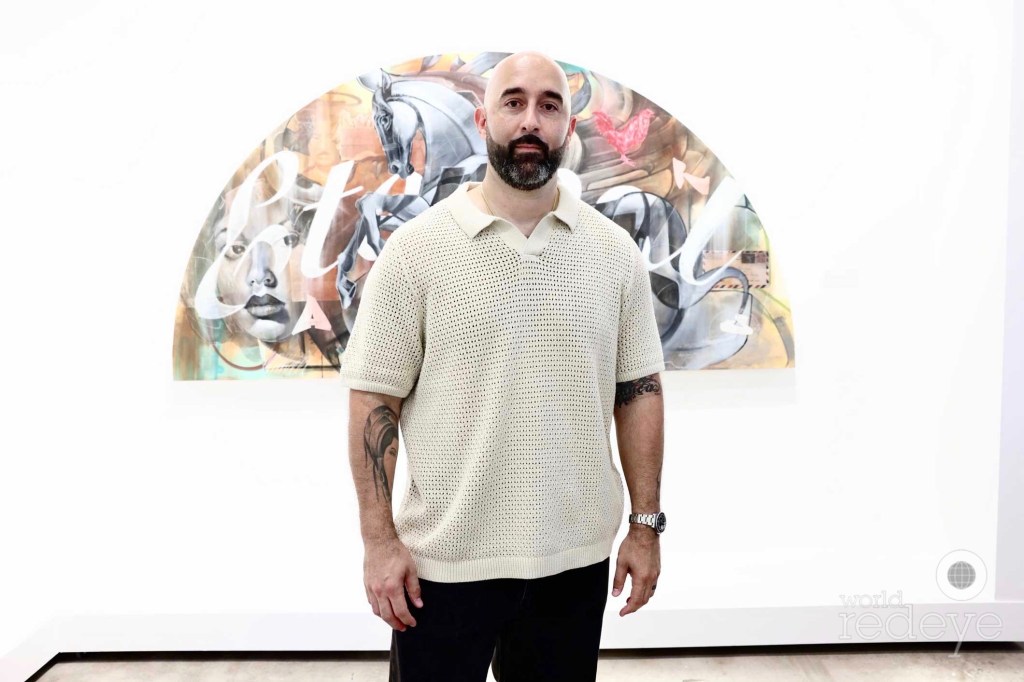 photo of artist ABSTRK posing in front of one of his works inside a gallery