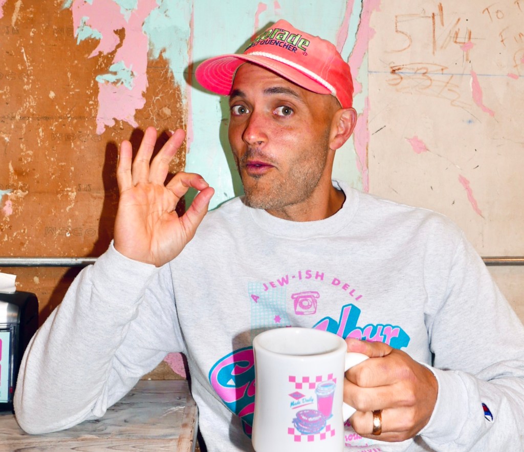 a man wearing a pink hat holding a coffee cup