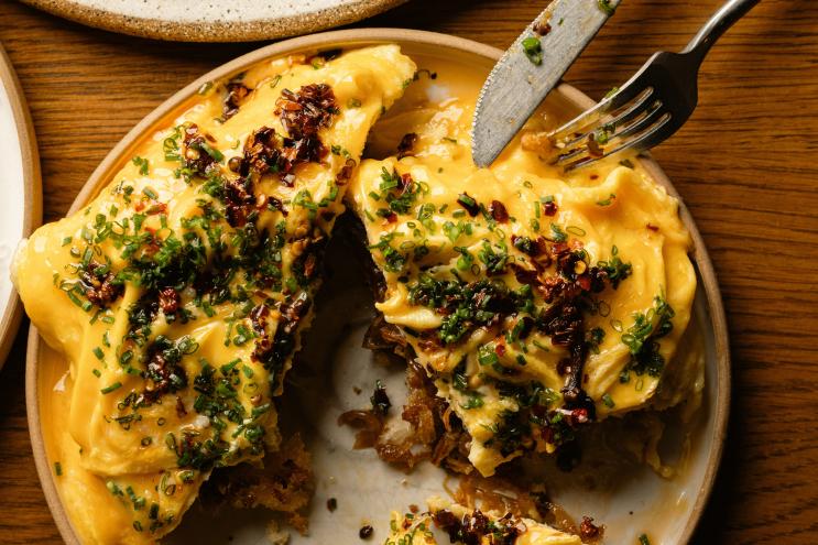a yellow egg dish with brown toppings on a ceramic plate