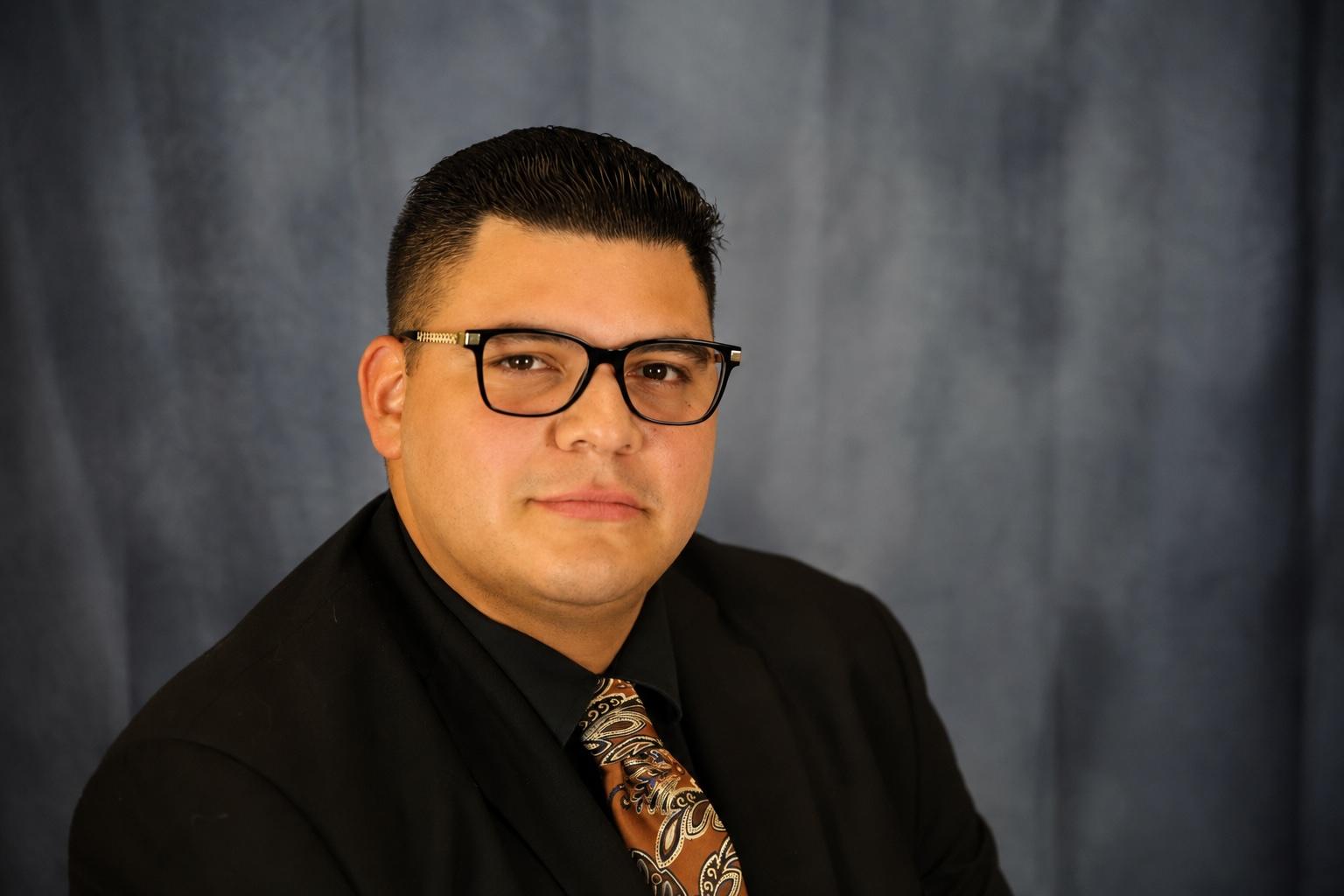 headshot of writer and law student Cesar Flores in a suit and glasses