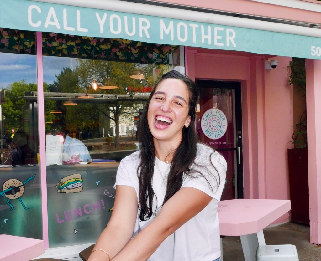 a woman smiling at the camera in front of a pink building