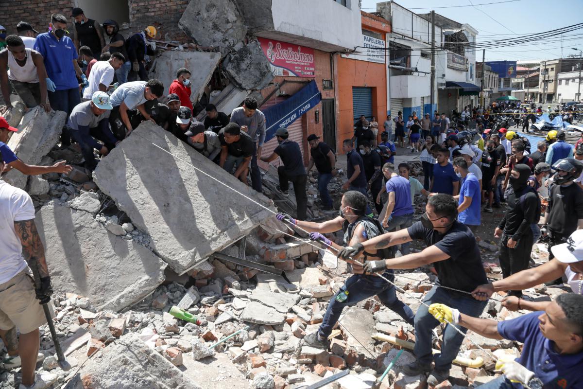 A photo of people lifting a large piece of concrete after an earthquake hit in Colombia.