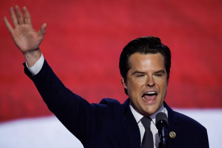 a man with dramatic eyebrows shouts and waves to a crowd