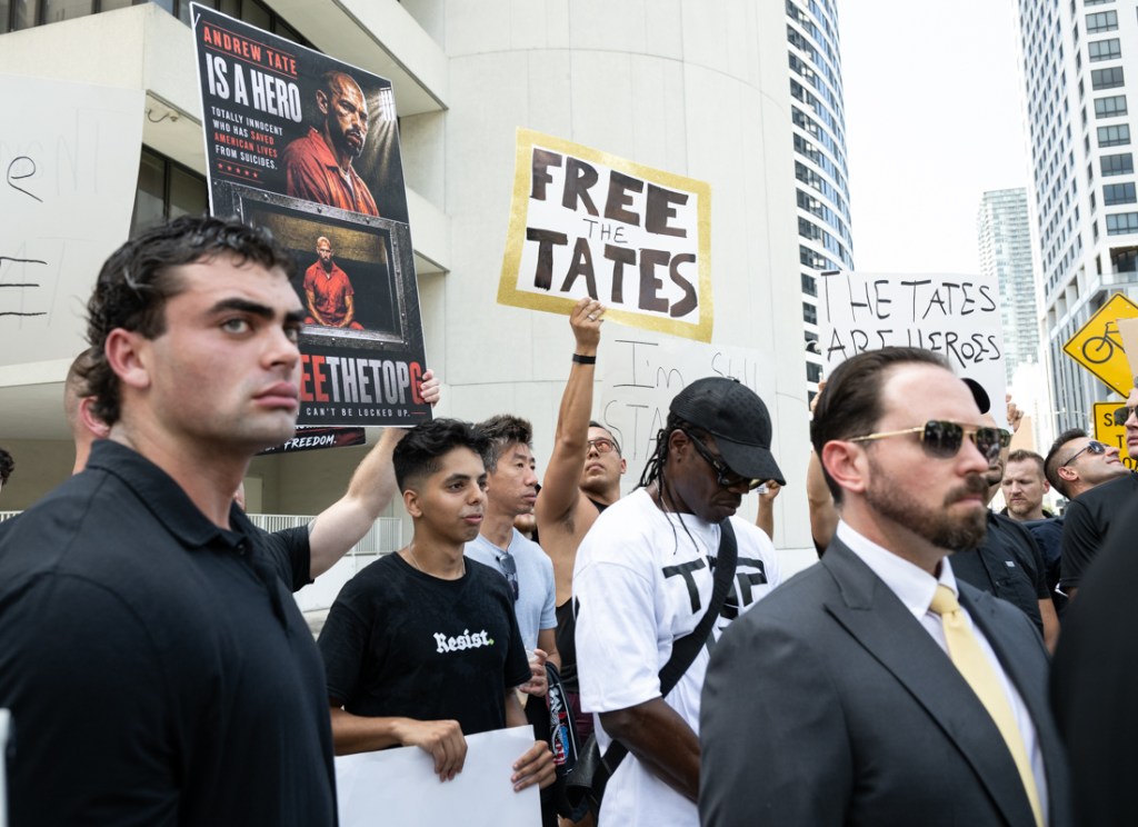 men hold signs supporting the Tate brothers in downtown Miami