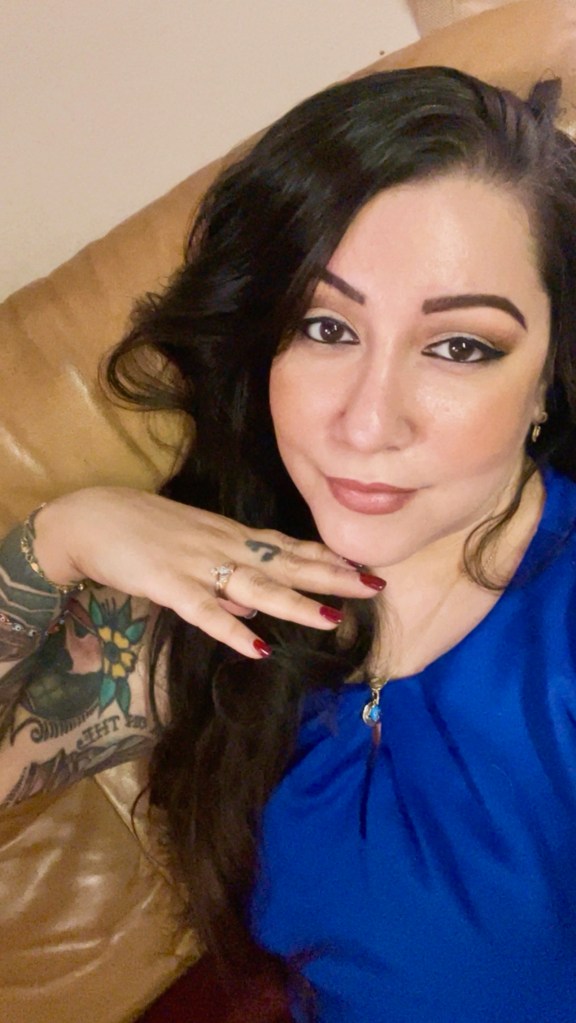 Portrait of a brunette woman looking at the camera wearing a blue shirt.