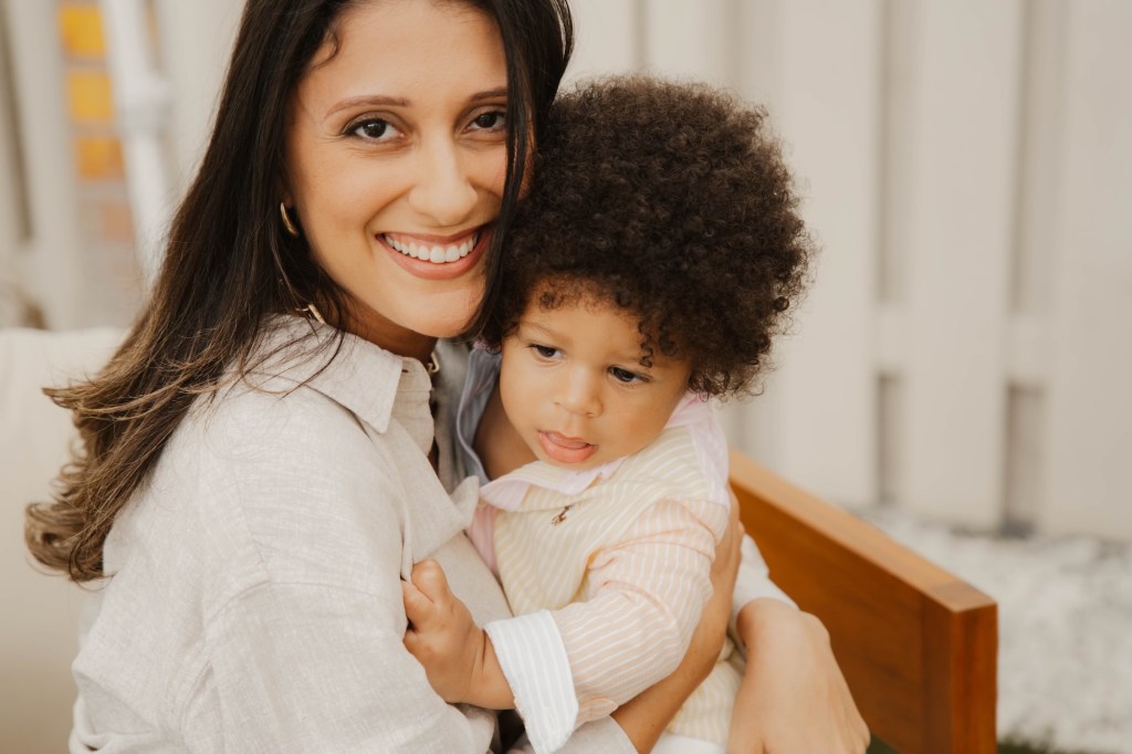 Photo of a woman wearing white holding a baby