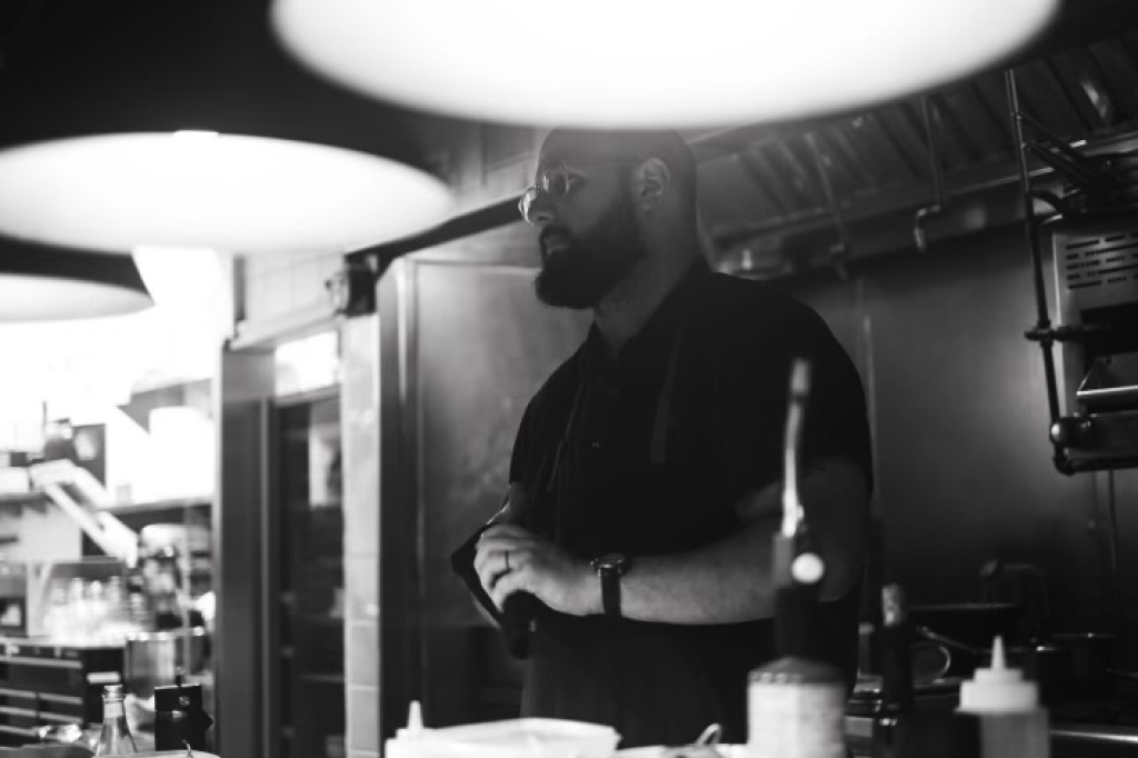 a black and white portrait of a man in a kitchen