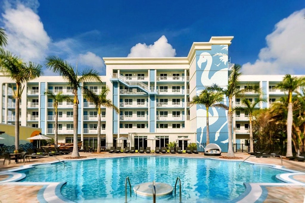 photo of the facade of a hotel with a pool in the foreground