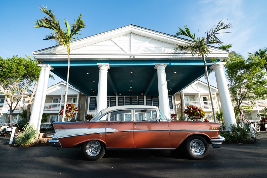 photo of the facade of a hotel with a classic car out front