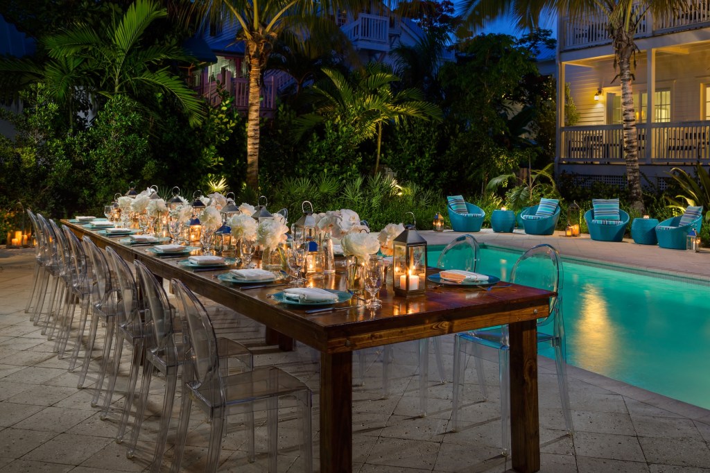 photo of a hotel pool area at night, with a dressed banquet table in the foreground
