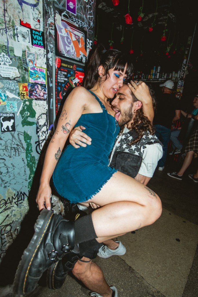 Photo of a man and a woman at a bar in Miami, the man is lifting the woman and kissing her chest