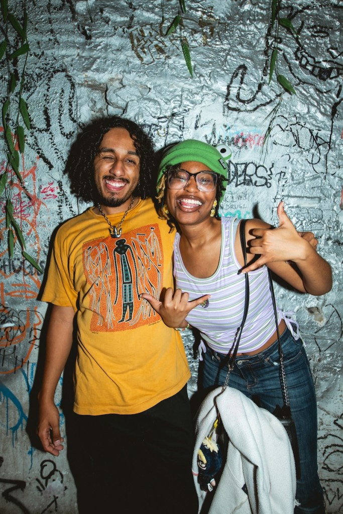 Photo of a man with a yellow shirt and a woman with a green hat smiling for the camera