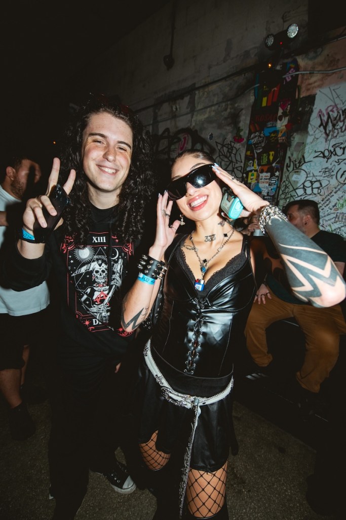 Photo of two people wearing black clothes posing for the camera at a Miami bar