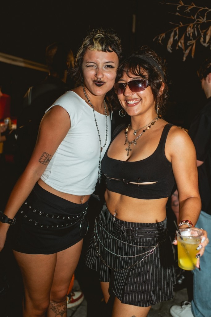 Photo of two women wearing short black skirts posing for the camera