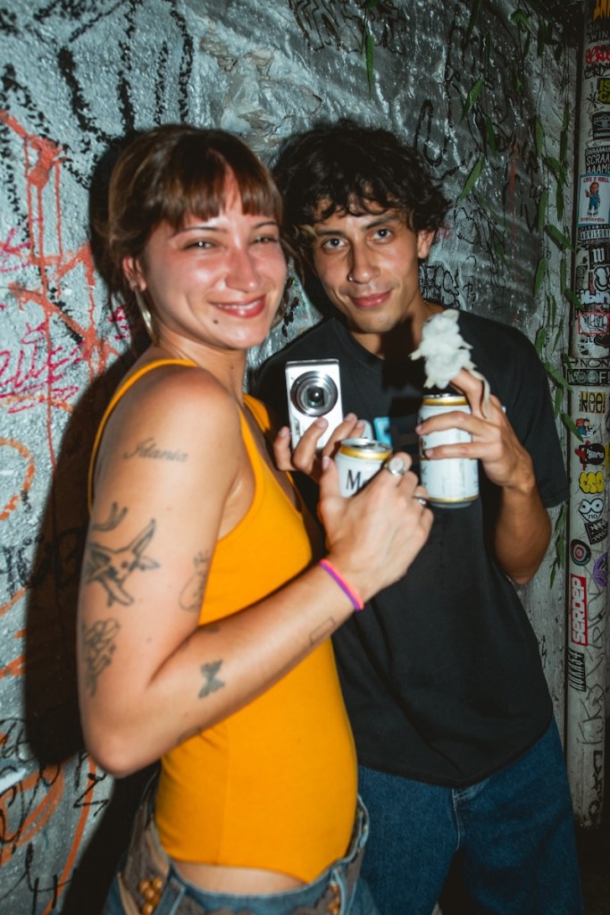 Photo of a man and a woman holding cans of modelo beer and smiling to the camera