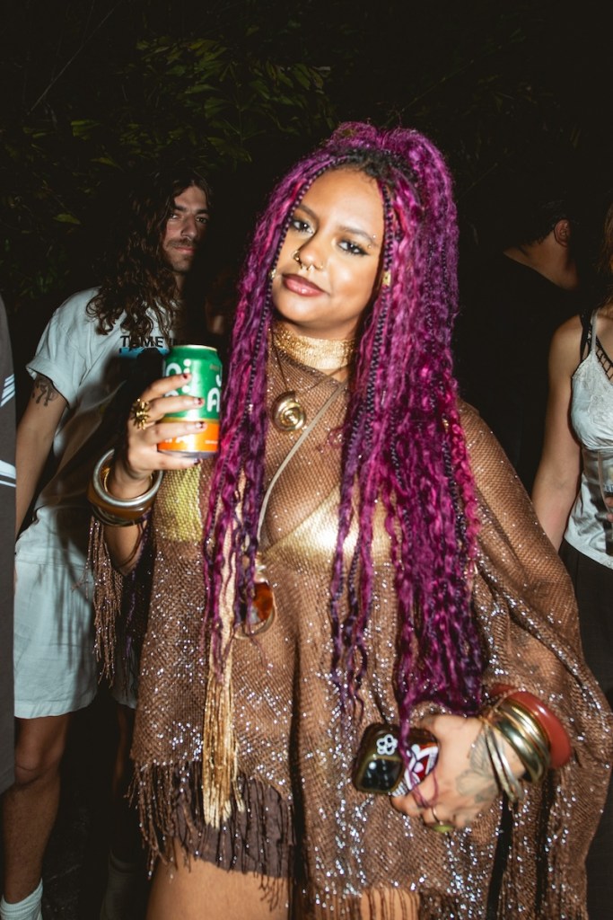 Photo of a woman with long pink hair holding a beer