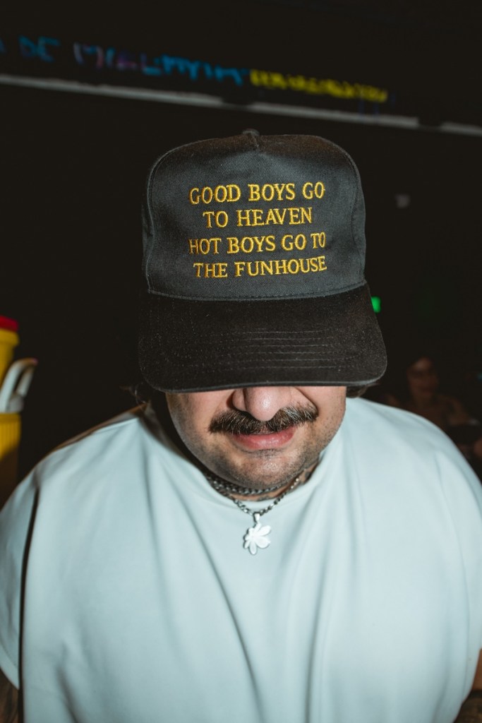 Man wearing a hat that reads Good boys go to heaven hot boys go to the funhouse