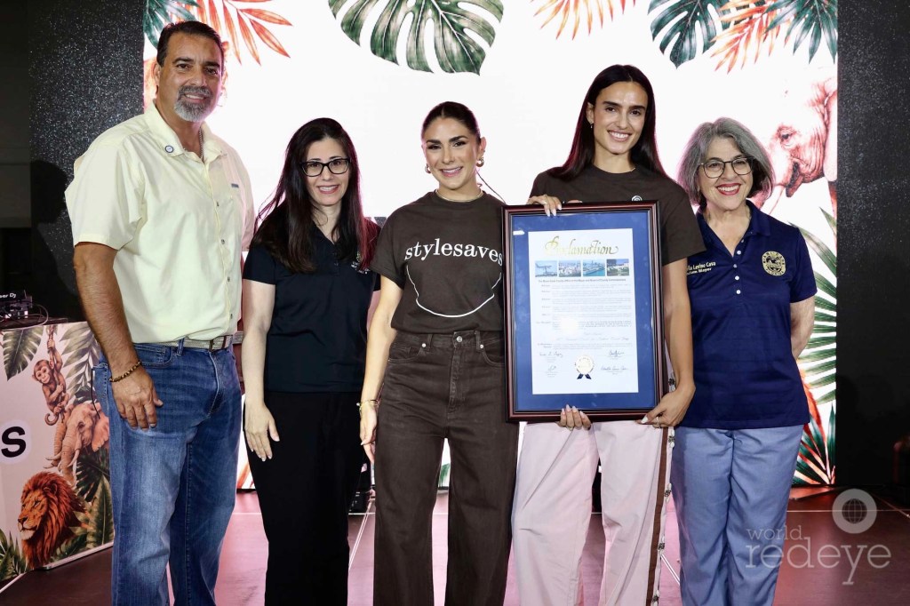 photo of four people posing with Miami-Dade County Mayor Daniella Levine Cava. The young woman next to the mayor holds a proclamation inside a plaque