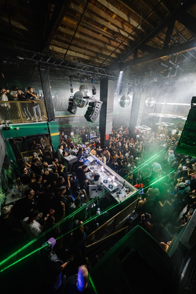 Photo of a venue in Miami that looks like a warehouse and a DJ performing in the middle